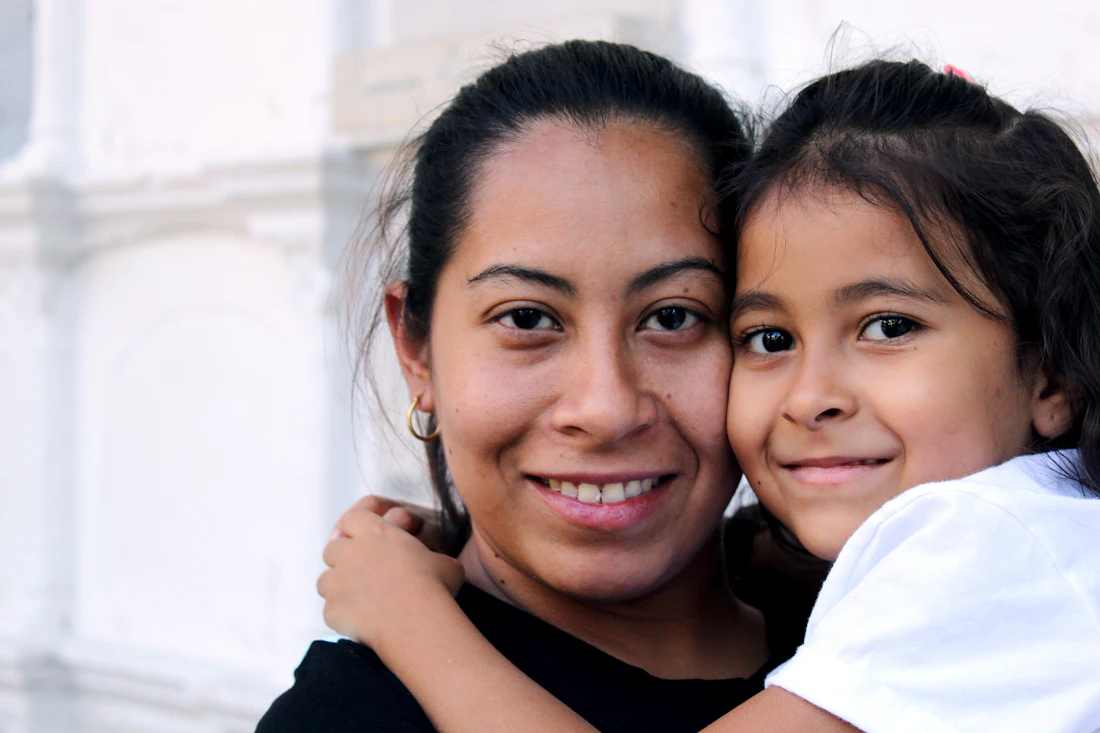 Una mamá y su hija abrazadas y sonriendo