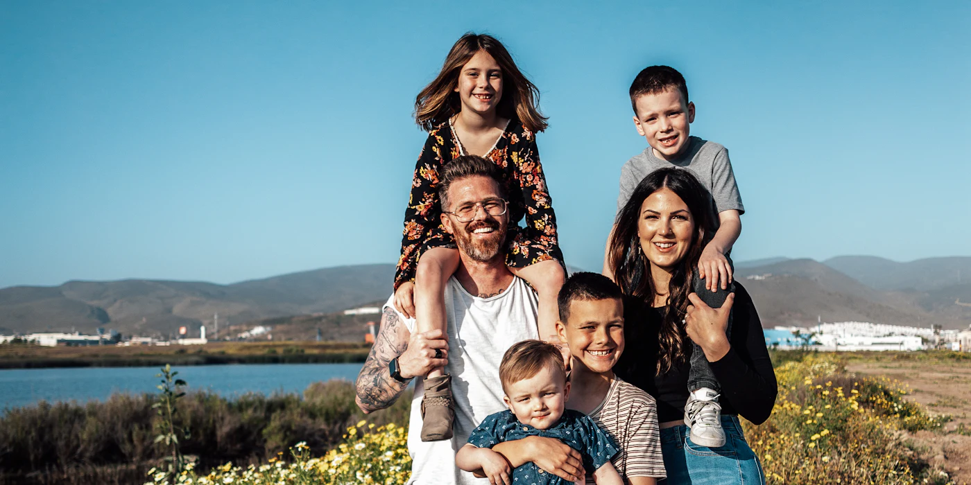 Una familia de seis personas sonriendo en un campo de flores en Ensenada, Baja California