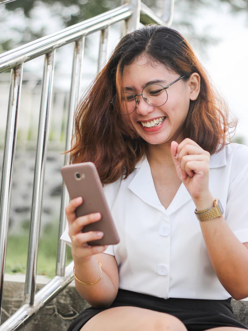 Una joven ríe mientras mira su teléfono